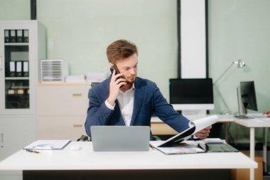 Ofiste dizüstü bilgisayarla çalışan genç bir iş adamı. İş, finans, muhasebe ve işyeri kavramları için mükemmel.