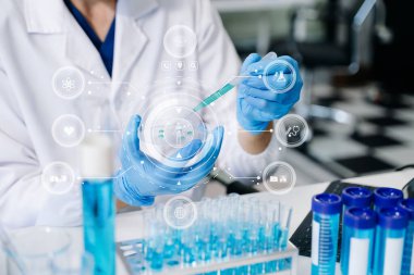 Bir tıp laboratuarında araştırma yapan genç bir bilim adamı, ön plandaki bir araştırmacı tıp laboratuarında bir mikroskop kullanıyor.. 