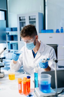 Kimya laboratuvarında kimyasal sıvıları karıştıran bir bilim adamı. Kimya laboratuvarında çalışan bir araştırmacı.