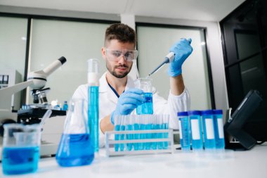 Bir tıp laboratuarında araştırma yapan genç bir bilim adamı, ön plandaki bir araştırmacı tıp laboratuarında bir mikroskop kullanıyor.. 