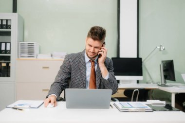Ofis masasında tablet ve dizüstü bilgisayarla finans analizi üzerinde çalışan kendine güvenen bir iş adamı. İş, muhasebe ve profesyonel iş yeri kavramları için mükemmel.