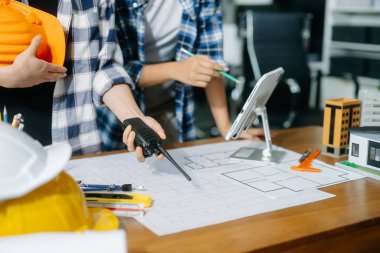 Çalışma ve tablet hakkında konuşan iki meslektaşım, ofisteki inşaat alanında mimari projeli dizüstü bilgisayar.