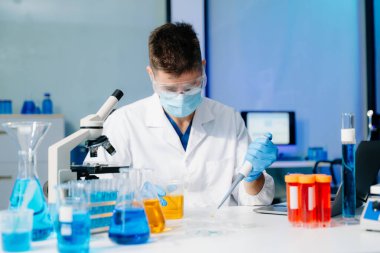 Kimya laboratuvarında kimyasal sıvıları karıştıran bir bilim adamı. Kimya laboratuvarında çalışan bir araştırmacı.