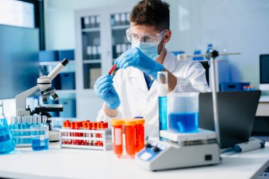 Modern tıbbi araştırma laboratuvarı. Erkek bilim adamı mikro pipetlerle çalışıyor. Biyokimyasal örnekleri analiz ediyor. Gelişmiş tıp kimya laboratuvarı..