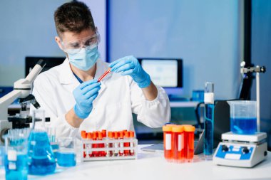 Modern tıbbi araştırma laboratuvarı. Erkek bilim adamı mikro pipetlerle çalışıyor. Biyokimyasal örnekleri analiz ediyor. Gelişmiş tıp kimya laboratuvarı..