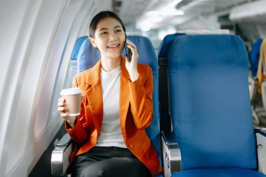 Genç Asyalı yönetici, dijital tablet, dizüstü bilgisayar ve akıllı telefondan birden fazla iş yaparak birinci sınıfta başarılı oluyor. Stil içinde seyahat et, zarafetle çalış.