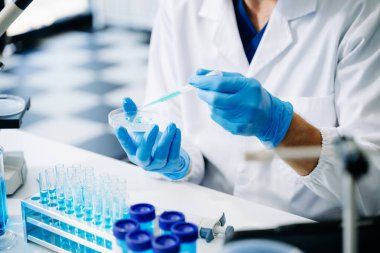 Bir tıp laboratuarında araştırma yapan genç bir bilim adamı, ön plandaki bir araştırmacı tıp laboratuarında bir mikroskop kullanıyor.. 