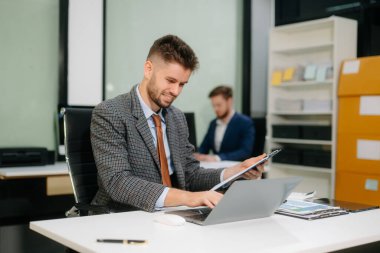 Ofis masasında tablet ve dizüstü bilgisayarla finans analizi üzerinde çalışan kendine güvenen bir iş adamı. İş, muhasebe ve profesyonel iş yeri kavramları için mükemmel.