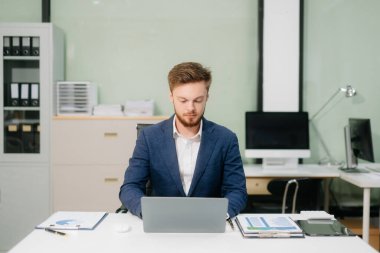 Kendine güvenen işadamı dizüstü bilgisayarla finans analizi üzerinde çalışıyor