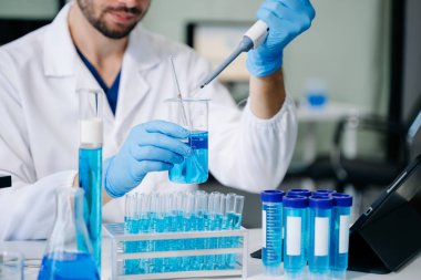 Modern tıbbi araştırma laboratuvarı. Erkek bilim adamı mikro pipetlerle çalışıyor. Biyokimyasal örnekleri analiz ediyor. Gelişmiş tıp kimya laboratuvarı..