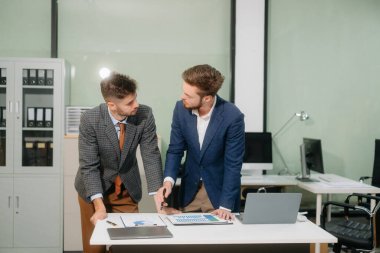 İki ofis arkadaşı, modern bir çalışma alanında yeni bir proje için fikir alışverişinde bulunuyor.                          