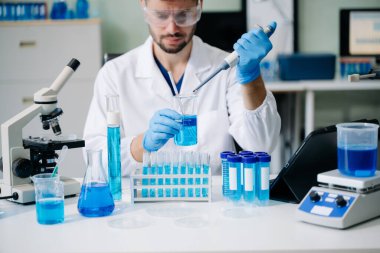 Modern tıbbi araştırma laboratuvarı. Erkek bilim adamı mikro pipetlerle çalışıyor. Biyokimyasal örnekleri analiz ediyor. Gelişmiş tıp kimya laboratuvarı..