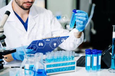 Erkek biyoteknoloji uzmanı, kimya laboratuarında çalışan yeni kimyasal maddeleri test ediyor.