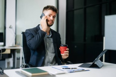 Ofiste dizüstü bilgisayarı, tableti ve notlarıyla çalışan profesyonel bir işadamı. İş, finans, muhasebe ve işyeri kavramları için mükemmel. 