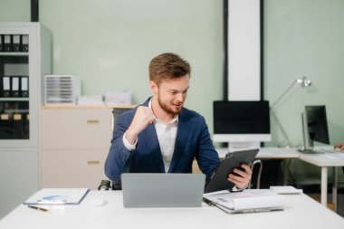 Ofiste tablet ve dizüstü bilgisayarla çalışan genç bir işadamı. İş, finans, muhasebe ve işyeri kavramları için mükemmel.