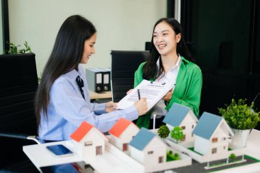 Mülk sektörünü dengelemek. Emlakçı müşteriye ev tasarımı ve satın alma anlaşmasını açıklıyor. Modern ofiste model evler