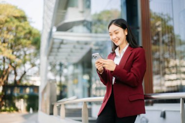 Genç Asyalı iş kadını lider girişimci, profesyonel yönetici büyük şehirde iş merkezinin arka planında dijital tablet bilgisayarı tutuyor..