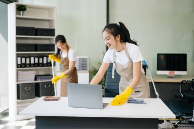 İki profesyonel temizlikçi bir gülümsemeyle şık bir yeri düzenliyor. Tertemiz bir ev ya da ofis için verimli ve dost canlısı ev temizleme hizmetleri