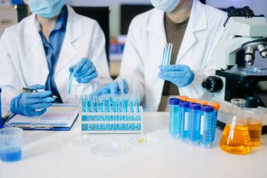 Laboratuar önlüklü bilim adamları, cam eşyalar üzerinde araştırma yapıyorlar ve modern, yüksek teknoloji laboratuvarında kimyasallarla çalışıyorlar..