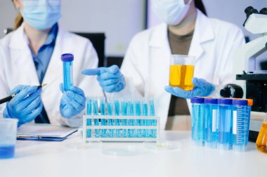 Bir tıp laboratuvarında araştırma yapan genç bilim adamları, ön plandaki bir araştırmacı, tıp laboratuarında bir mikroskop kullanıyor..  