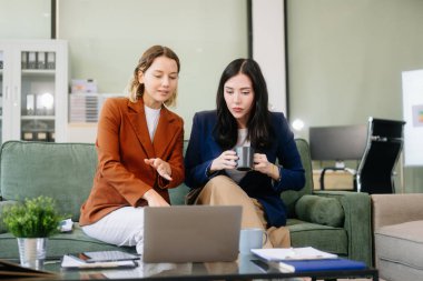 İki iş kadını şık bir ofis ortamında dizüstü bilgisayar kullanarak iş birliği yapıyor. Takım çalışması, liderlik ve yaratıcılık kavramları için mükemmel..