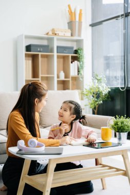 Neşeli anne ve kız kanepede güzel vakit geçiriyorlar, gülümsüyorlar ve birlikte kitap okuyorlar. Aile teması için mükemmel.