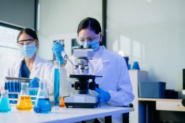 İki Asyalı kadın bilim adamı analiz sonuçları laboratuarda inceleniyor ve analiz ediliyor.