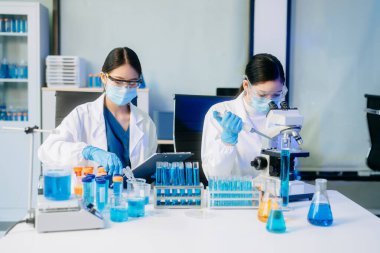 İki Asyalı kadın bilim adamı analiz sonuçları laboratuarda inceleniyor ve analiz ediliyor.