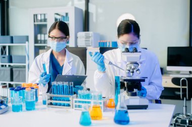 İki Asyalı kadın bilim adamı analiz sonuçları laboratuarda inceleniyor ve analiz ediliyor.