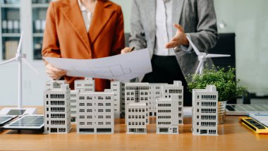 Neare 'de oturan çeşitli etnik çeşitliliğe sahip iş adamlarından oluşan bir ekip konut projesinin modeline bakıyor. Yeşil iş şirketi ve Güneş Enerjisi Çevre Kenti Kavramı