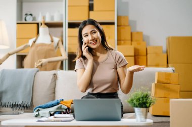 Genç işyeri sahibi kadın paket kutusunu hazırla ve tablet, dizüstü bilgisayar alışverişi online konsept üzerinden müşteriye teslimat için çevrimiçi kontrol yap.