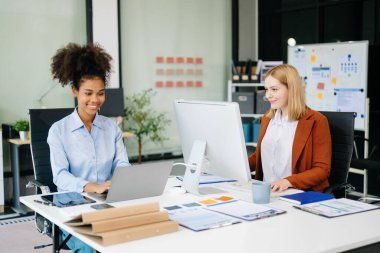 Bayan meslektaşımla yeni projeyi tartışıyoruz. Genç bir kadın ofiste genç bir Afrikalı kadınla konuşuyor..