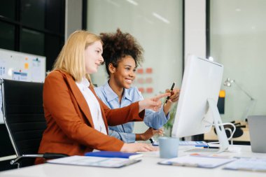 Bayan meslektaşımla yeni projeyi tartışıyoruz. Genç bir kadın ofiste genç bir Afrikalı kadınla konuşuyor..