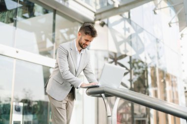 Başarılı bir iş adamı dışarıda dizüstü bilgisayar ve iş merkezi geçmişi ile çalışır.