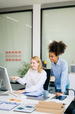 İş kadını takım toplantısını yönetiyor ve birlikte çalışma ofisinde mali durumuyla birlikte tablet ve dizüstü bilgisayar kullanıyor