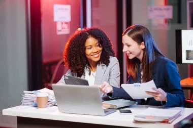 Nazik yönetici yönetici, gece geç saatlerde modern ofiste Afrika kökenli Amerikalı kadın pazarlama yöneticisiyle iş çözümlerini paylaşır ve tartışır.. 