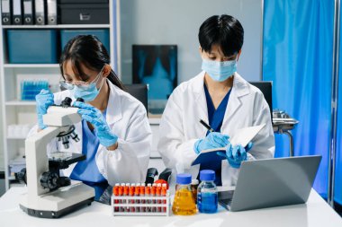 Laboratuar önlüklü bilim adamları, cam eşyalar üzerinde araştırma yapıyorlar ve modern, yüksek teknoloji laboratuvarında kimyasallarla çalışıyorlar.