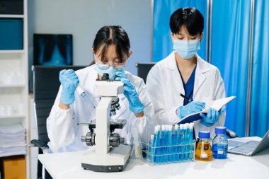 Laboratuar önlüklü bilim adamları, cam eşyalar üzerinde araştırma yapıyorlar ve modern, yüksek teknoloji laboratuvarında kimyasallarla çalışıyorlar.