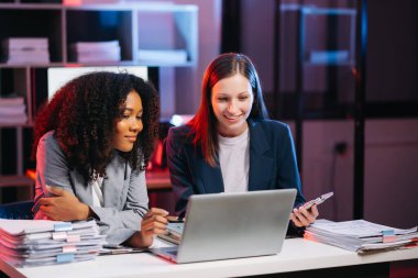 Nazik yönetici yönetici, gece geç saatlerde modern ofiste Afrika kökenli Amerikalı kadın pazarlama müdürüyle iş çözümlerini paylaşır ve tartışır.. 