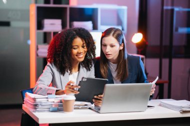 Nazik yönetici yönetici, gece geç saatlerde modern ofiste Afrika kökenli Amerikalı kadın pazarlama yöneticisiyle iş çözümlerini paylaşır ve tartışır.. 