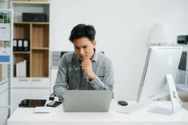 Modern ofiste dizüstü bilgisayarla çalışan genç, konsantre yakışıklı bir adam.