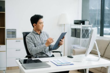 Genç yakışıklı adam modern ofiste pano ile çalışıyor.