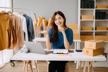 Startup small business SME, Entrepreneur owner woman using smartphone or tablet taking receive and checking online purchase shopping order to preparing pack product box.