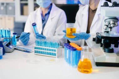 Bir tıp laboratuvarında araştırma yapan genç bilim adamları, ön plandaki bir araştırmacı, tıp laboratuarında bir mikroskop kullanıyor..  