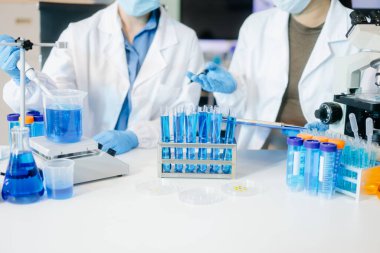 Bir tıp laboratuvarında araştırma yapan genç bilim adamları, ön plandaki bir araştırmacı, tıp laboratuarında bir mikroskop kullanıyor..  