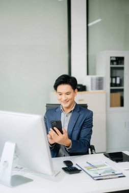 Asyalı işadamı tabletleri, laptopları ve ofiste yaptıkları işlerden memnun ve memnun.