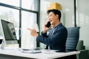 Asyalı işadamı tabletleri, laptopları ve ofiste yaptıkları işlerden memnun ve memnun.