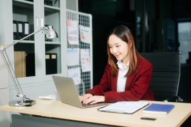 Çalışan not defteri, tablet ve dizüstü bilgisayarla çalışan genç Asyalı iş kadını akıllı telefon, tablet ve dizüstü bilgisayarla konuşuyor. 