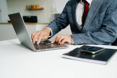 İş adamının elinin orta bölümü ofis ayarlarında dizüstü bilgisayarla çalışıyor. 