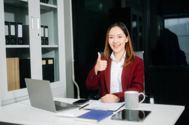 Çalışan not defteri, tablet ve dizüstü bilgisayarla çalışan Asyalı iş kadını 